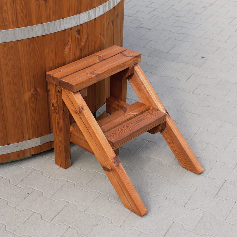 Standard wooden step ladder against a wooden barrel on a tiled floor