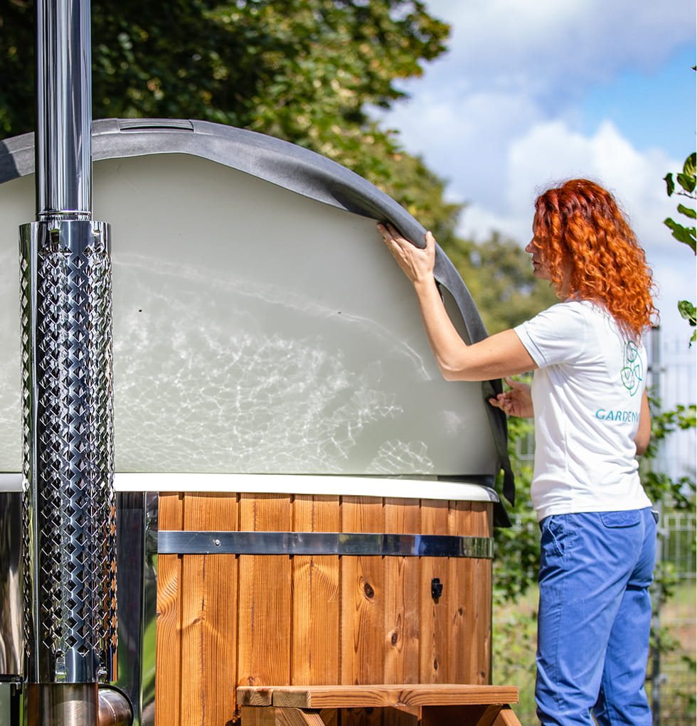 A woman puts a cover on the hot tub on a sunny day