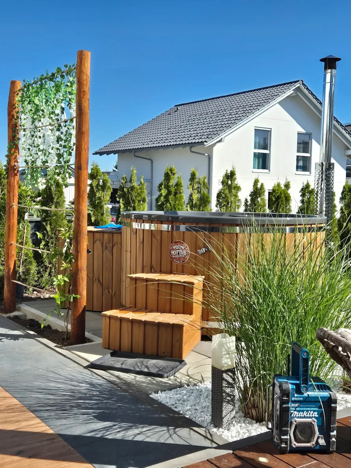 Gardenvity wood fired hot tub installed in a private garden with wooden steps and greenery.